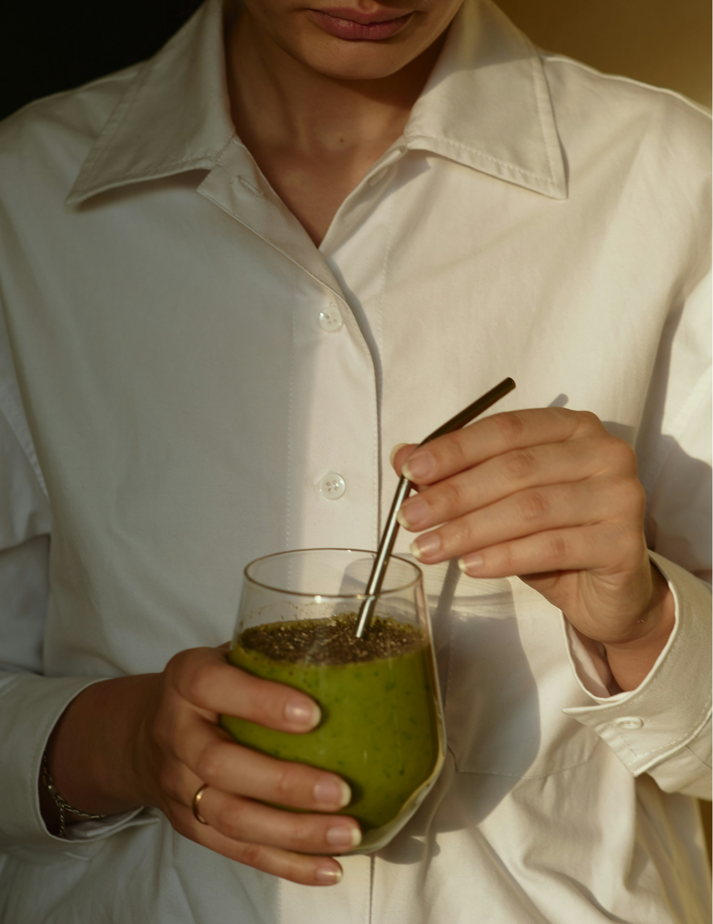 Woman in a white top holding a matcha drink